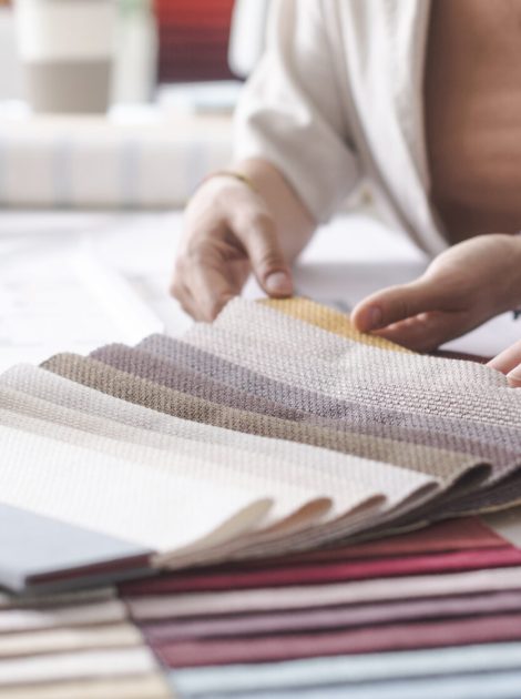 Interior designers working together on a project in their office: they are checking fabric samples and picking the right color palette, hands close up